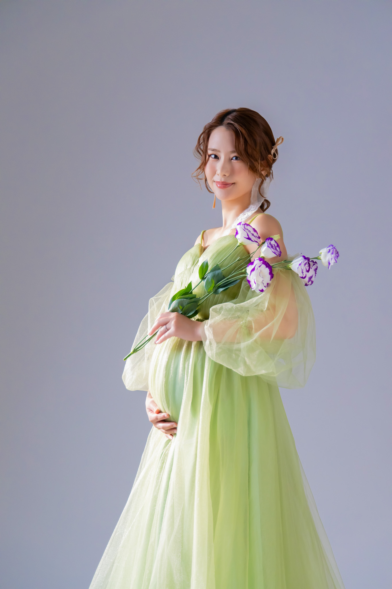 レースのプレミアムドレスをまとい、花束を手にした立ち姿