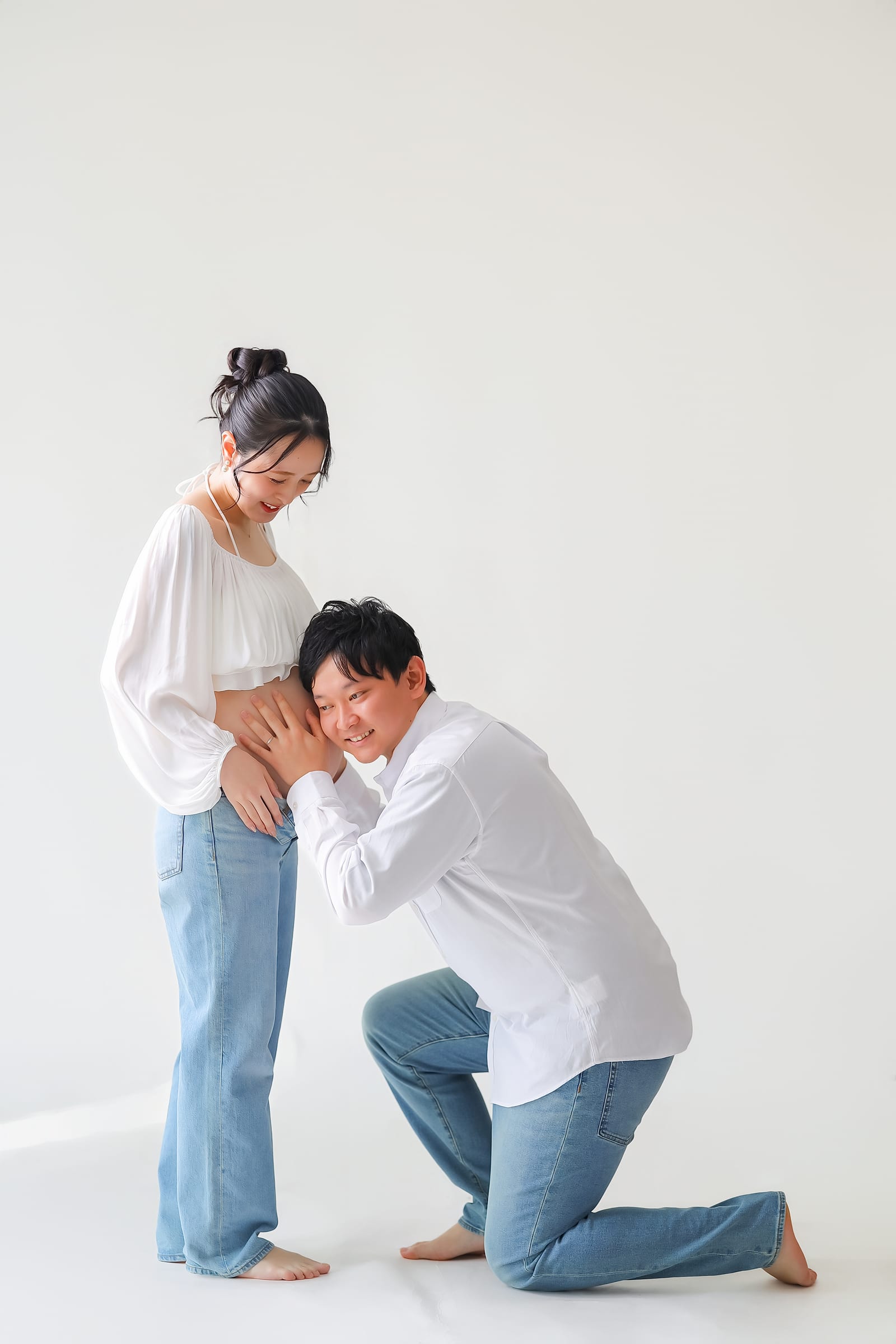 お腹に耳を当てるご主人と、それを見下ろす妊婦