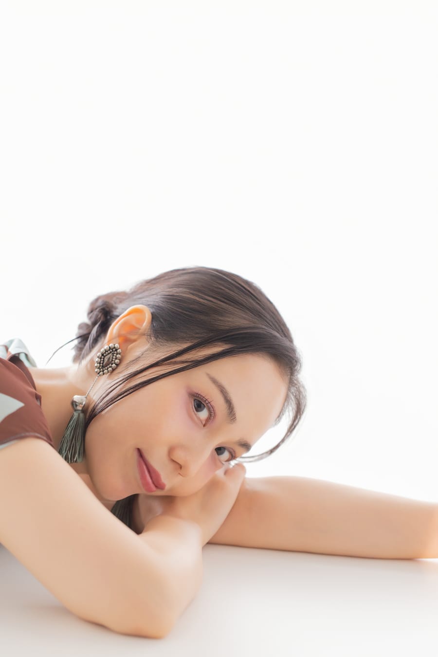 白い背景で腕に頭をのせ、正面を向いたプロフィール写真
