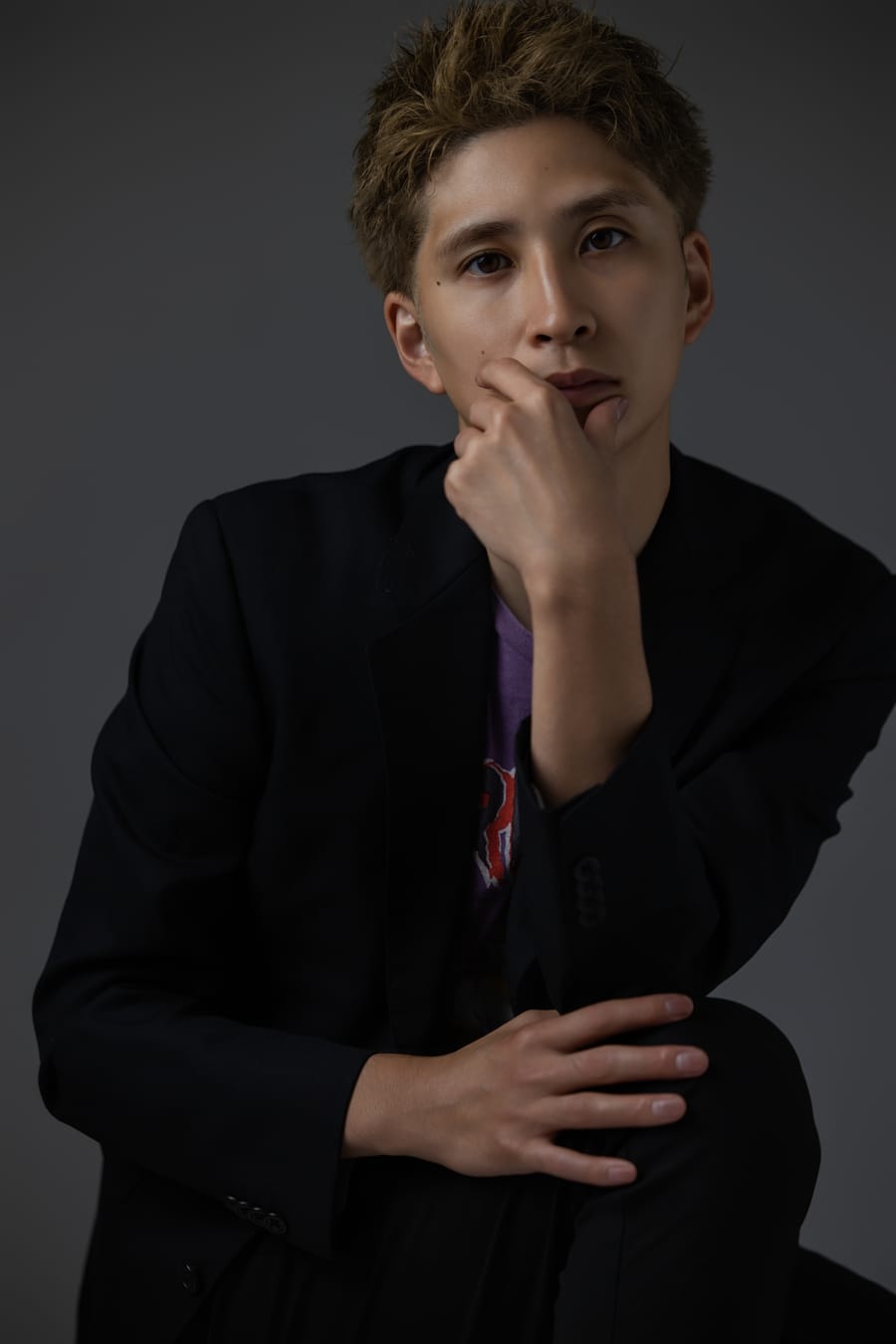 黒いジャケットの男性を暗い背景で撮影した、ビジネス向けのプロフィール写真