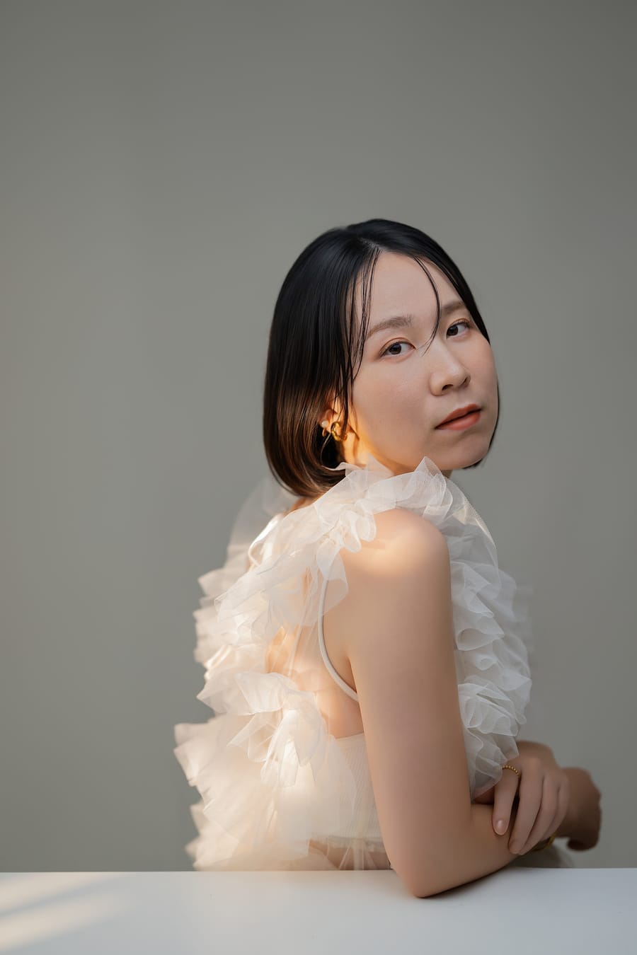 肩越しに振り返った、白いフリルのトップスのプロフィール写真